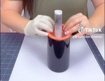 A woman puts a tumbler protector on her cup's rim